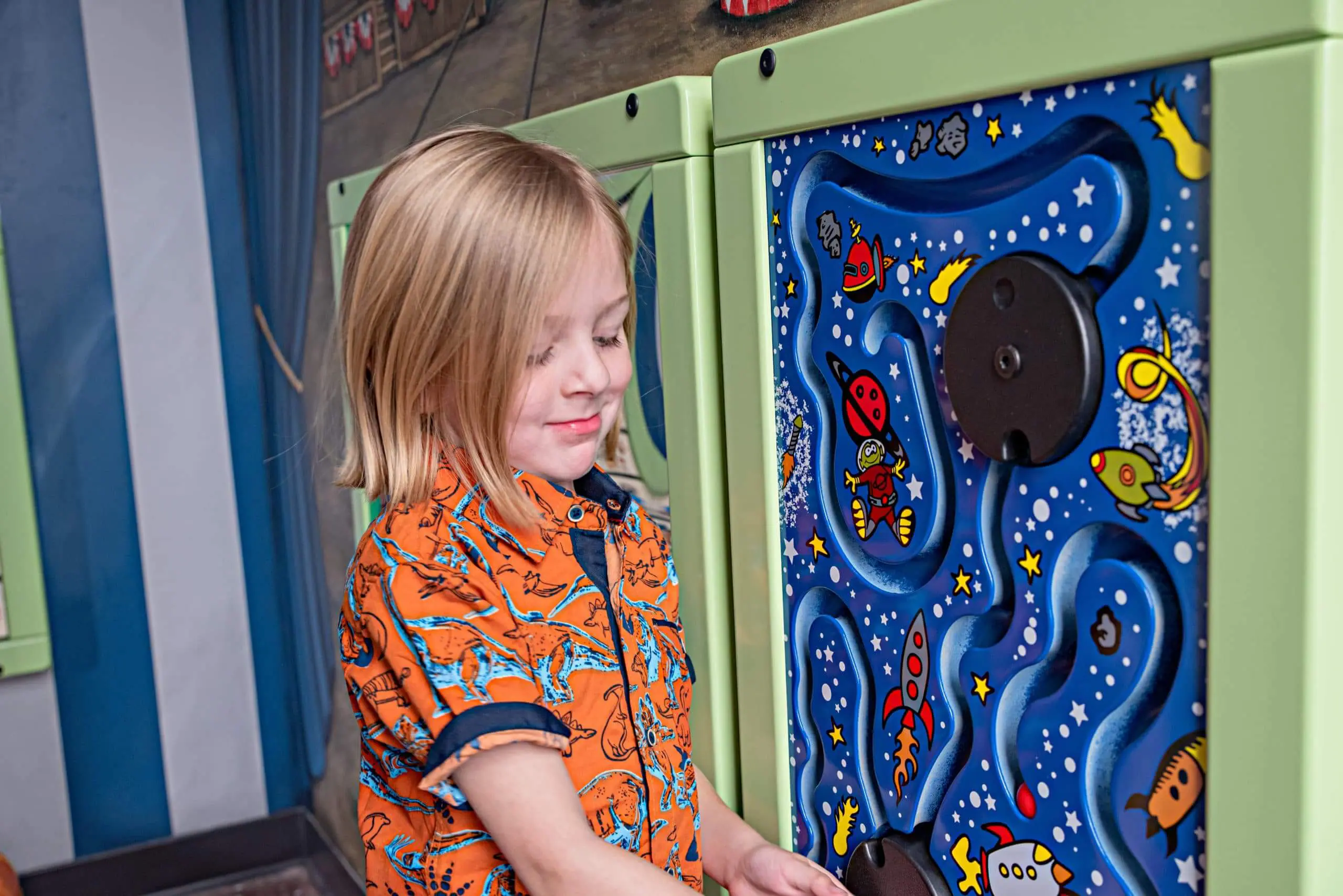 Child exploring a playful wall activity at Utah Children's Dentistry
